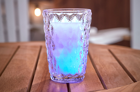 blue and purple glass candle on wooden table