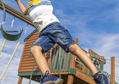 boy jumping onto blue rubber mulch on playground